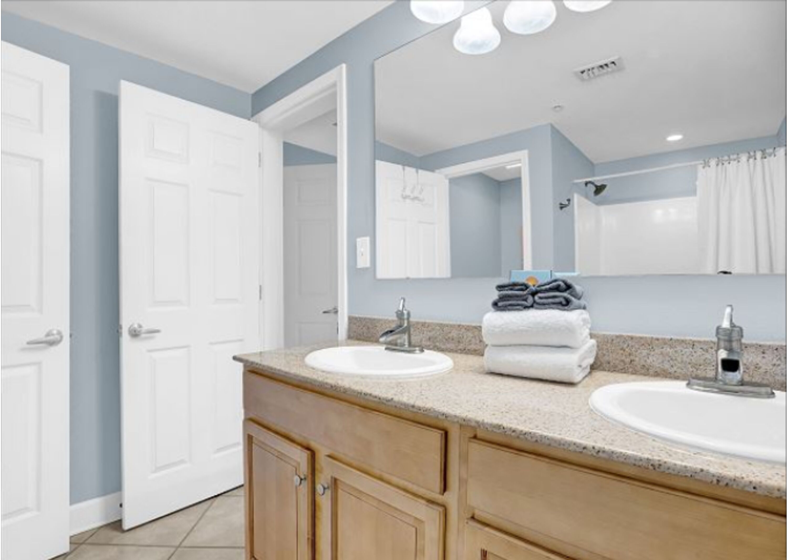 A bathroom with two sinks, a mirror, and a towel stack.