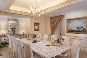 A formal dining room with a chandelier, a large painting, and a buffet table with fruits and glasses. - New Madinah Hotel (Madinah)