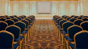 A conference room with rows of blue chairs and a carpeted floor. - New Madinah Hotel (Madinah)