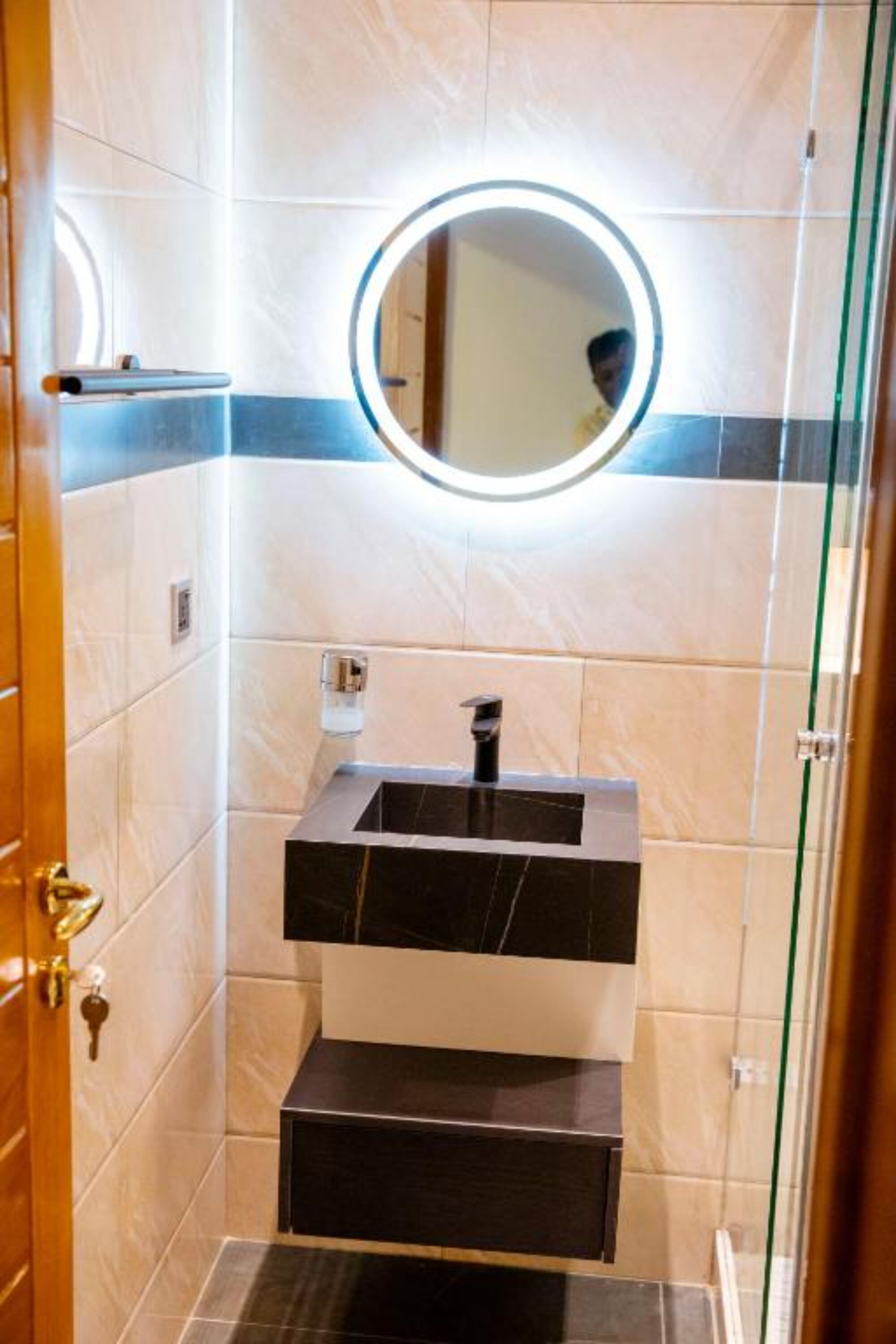 A bathroom with a sink, mirror, and tiled walls.