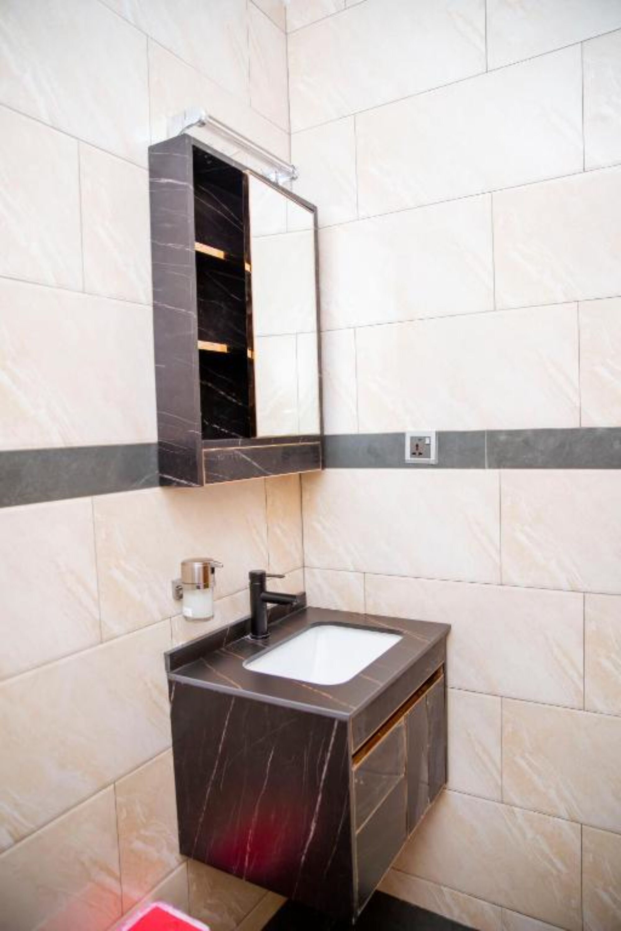 A bathroom with a marble sink, a mirror, and a towel dispenser.