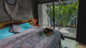 Een slaapkamer met een bed, een wanddecoratie en uitzicht op groen.