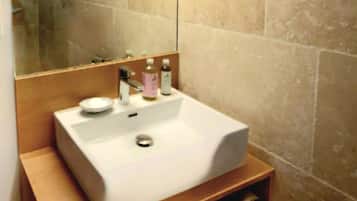 Une salle de bain avec un lavabo blanc, un miroir et des murs recouverts de carreaux beiges.