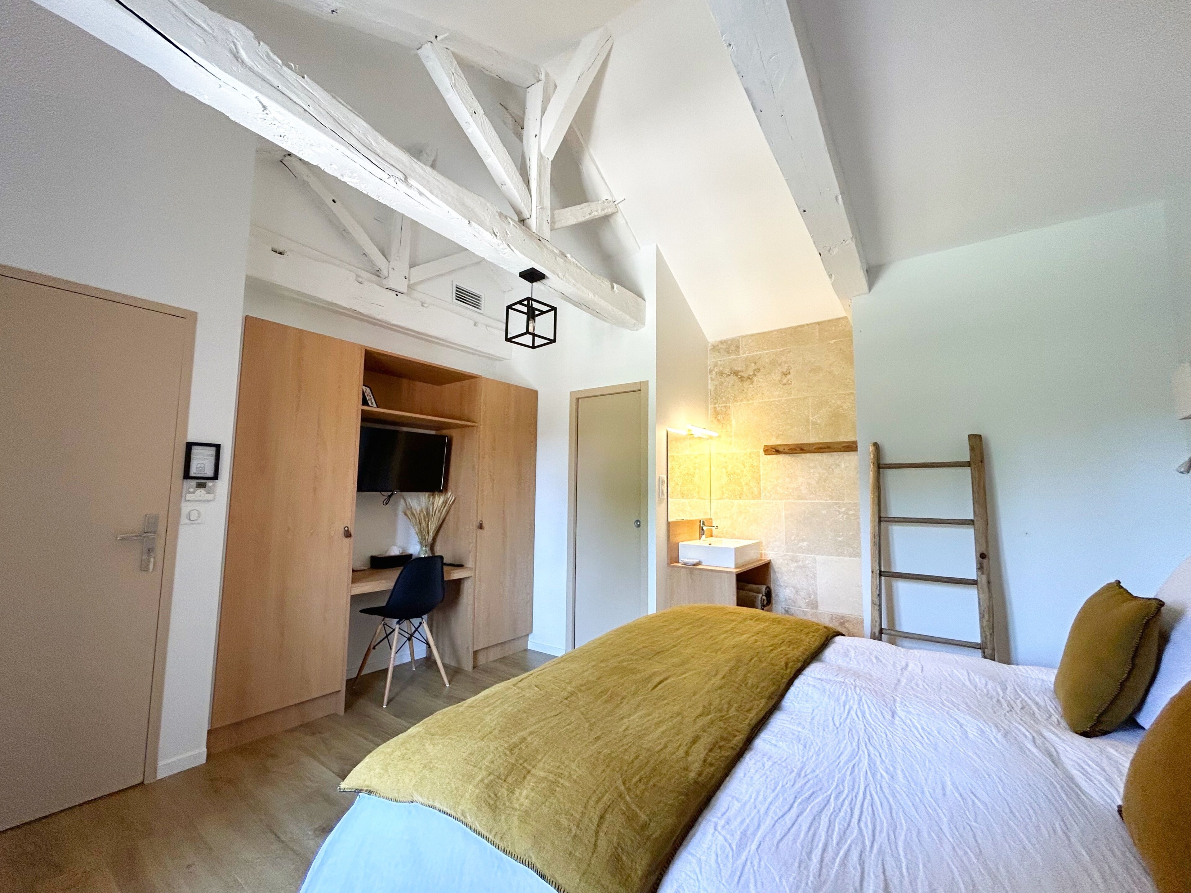 A bedroom with a bed, a desk, a wardrobe, and a bathroom.
