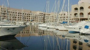 A marina with multiple boats docked, a large building with multiple balconies in the background, and clear skies. - Studio at Hyères Port with loggia and parking (Hyères)