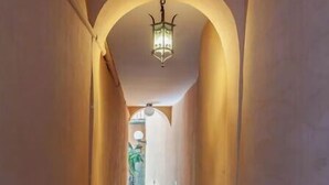 Um corredor estreito com soalho de pedra e uma única luminária no teto.