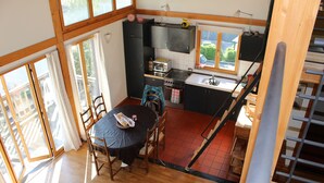 Une cuisine compacte avec un coin repas, de grandes fenêtres et un escalier.