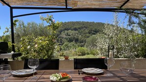 A table set for two with plates, cutlery, and glasses, overlooking a scenic landscape with trees and hills. - Pretty villa in the Bandol vineyards, 15 minutes from the beaches. (Le Beausset)