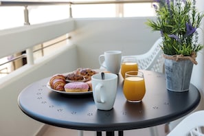 A table with croissants, a mug, and a glass of orange juice on a balcony.