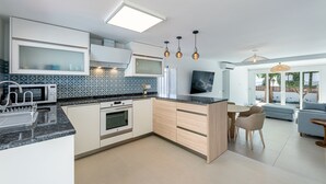 Eine moderne Küche mit integriertem Mikrowellenherd, Backofen und Spüle, sowie ein Essbereich mit Tisch und Stühlen.