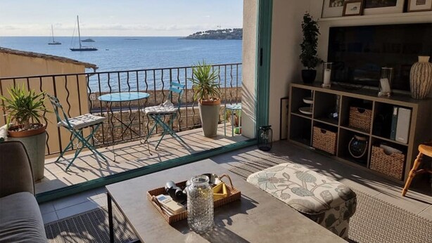 Ein Balkon mit Meerblick, ein Tisch mit Korb und eine Couch.