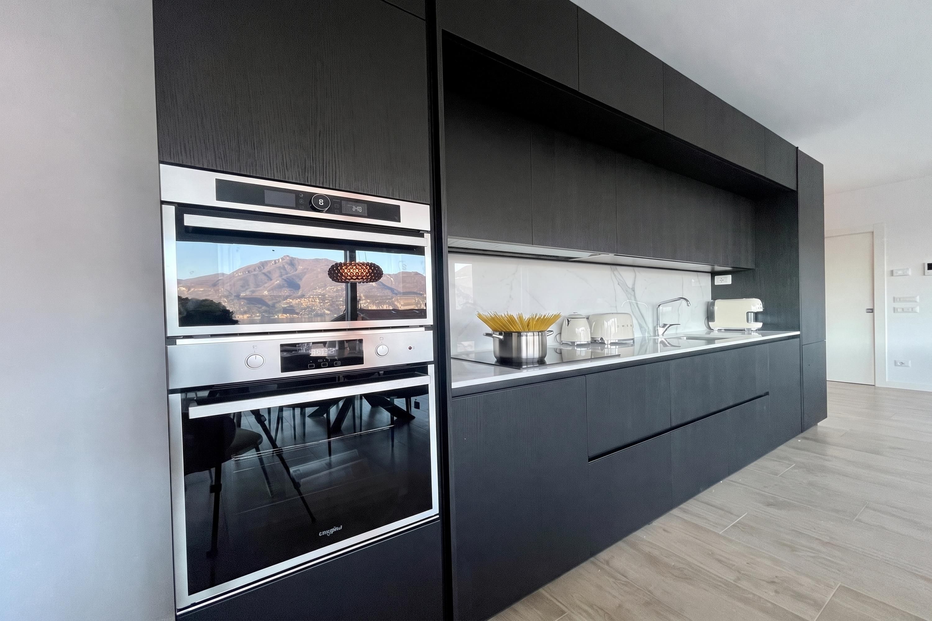 A modern kitchen with built-in appliances, a view of mountains, and a minimalist design.