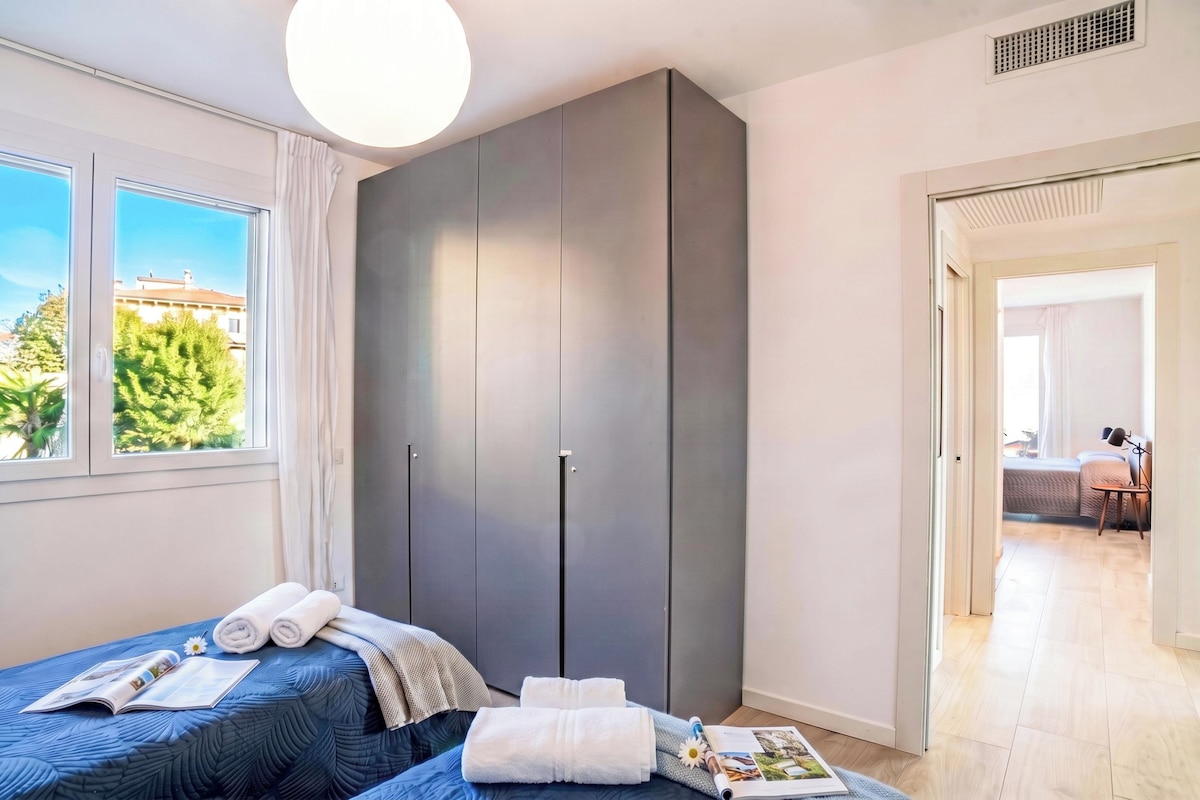 A bedroom with a bed, a wardrobe, a window with curtains, and a view of the outside.