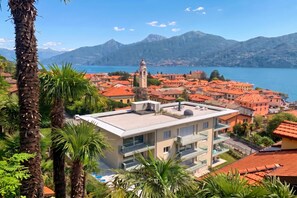 A coastal town with red-roofed buildings, a prominent clock tower, and a mountain backdrop. - Modern House Apartments (Menaggio)