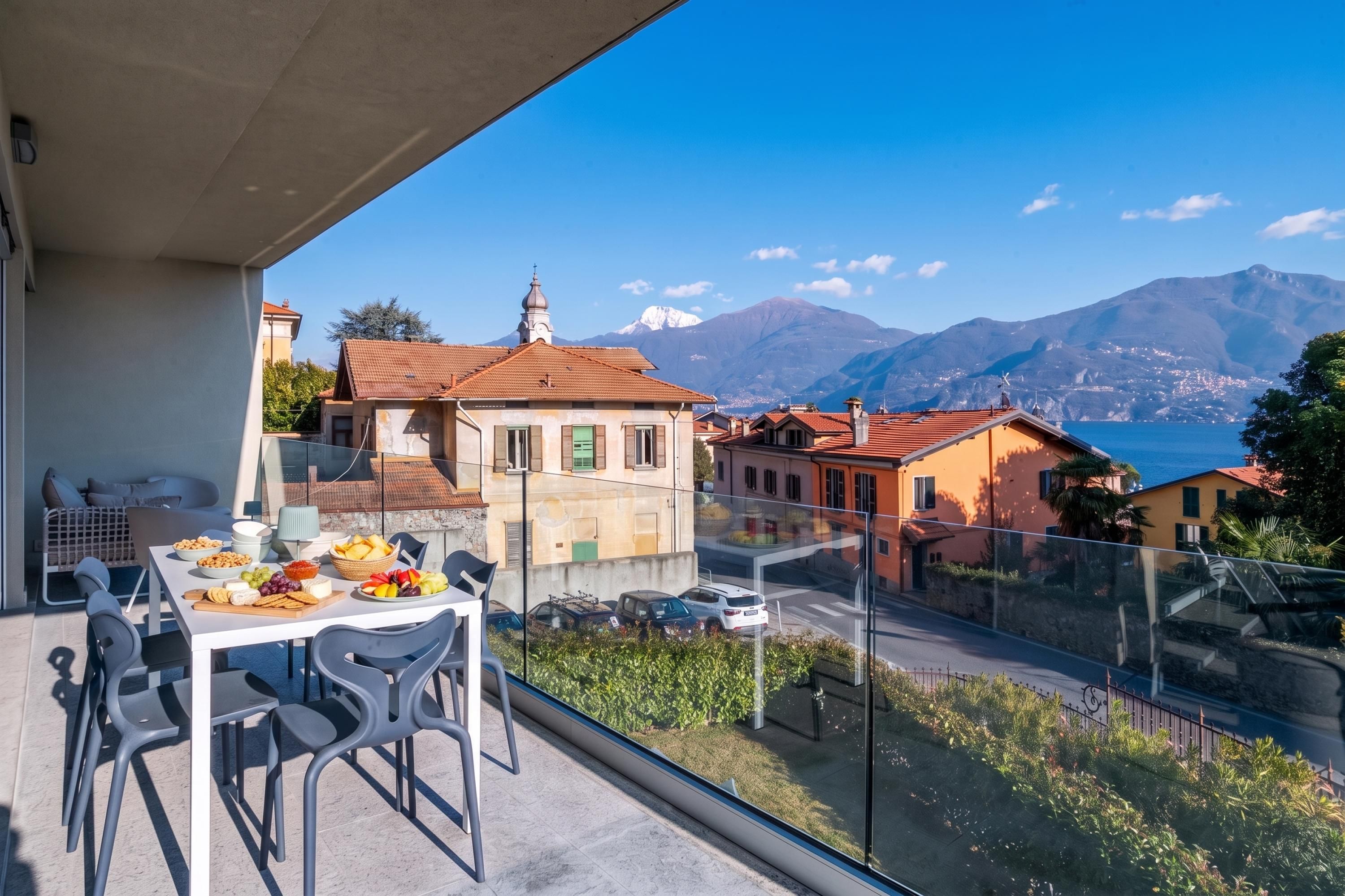 Ein Balkon mit Essplatz, mit Blick auf eine Berglandschaft und ein Gewässer.