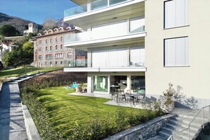 A modern building with a flat roof, a balcony, and a well-maintained lawn.