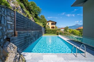 Una piscina con un muro de piedra y vistas a la montaña.