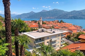 A coastal town with red-roofed buildings, a prominent clock tower, and a mountain backdrop. - Modern House Apartments (Menaggio)