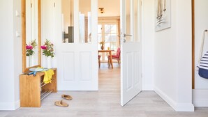 A hallway with a wooden bench, a mirror, and a door leading to a dining area with a table and chairs. - Ferienhaus Seeadler 34 - Der Natur Ganz nah (Fuhlendorf)