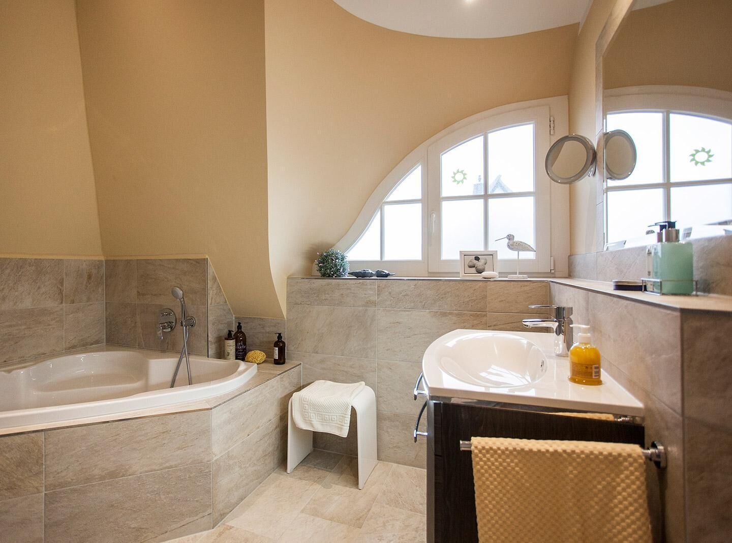Une salle de bain moderne avec une baignoire sur pieds, un meuble-lavabo et une grande fenêtre qui laisse entrer la lumière naturelle.