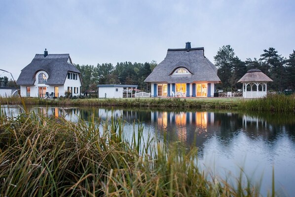 Une propriété au bord du lac comprenant plusieurs maisons, un belvédère et un étang.