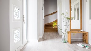 A hallway with a wooden staircase, a mirror, a wooden console table, and a vase with flowers. - Ferienhaus Seeadler 7 - Der Natur Ganz nah (Fuhlendorf)