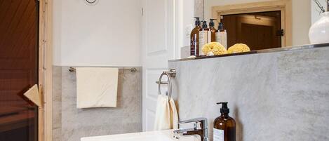Un baño moderno con un lavamanos grande de color blanco, un espejo y una puerta de madera.