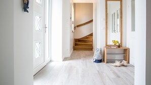Ein Flur mit einer Holztreppe, einem Spiegel und einem kleinen Tisch mit einer Vase und Büchern.