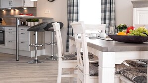 Una cocina moderna con armarios blancos, encimera de madera y comedor con sillas y banco blancos.