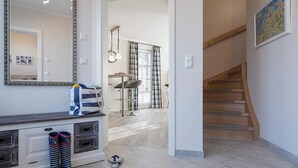 Un interior moderno con una escalera, un área de comedor y un pasillo que lleva a otra habitación.