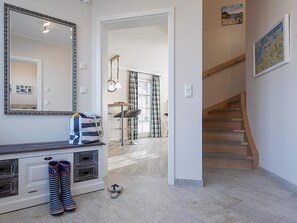 Un intérieur moderne comprenant un escalier, un coin repas et un couloir menant à une autre pièce.