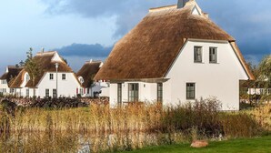 A row of white houses with thatched roofs and a grassy foreground. - Ferienhaus Seeschwalbe 37 - Der Natur Ganz nah (Fuhlendorf)