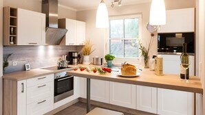 A modern kitchen with white cabinets, a wooden countertop, and two pendant lights. - Ferienhaus Seeschwalbe 37 - Der Natur Ganz nah (Fuhlendorf)