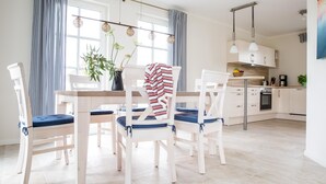 A modern kitchen with white cabinets, a built-in oven, and a coffee machine. - Ferienhaus Schilfrohrsänger 31 - Der Natur Ganz nah (Fuhlendorf)