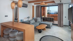 Un salón moderno con una mesa de comedor de madera, sofás grises y un ventanal con vistas al mar.