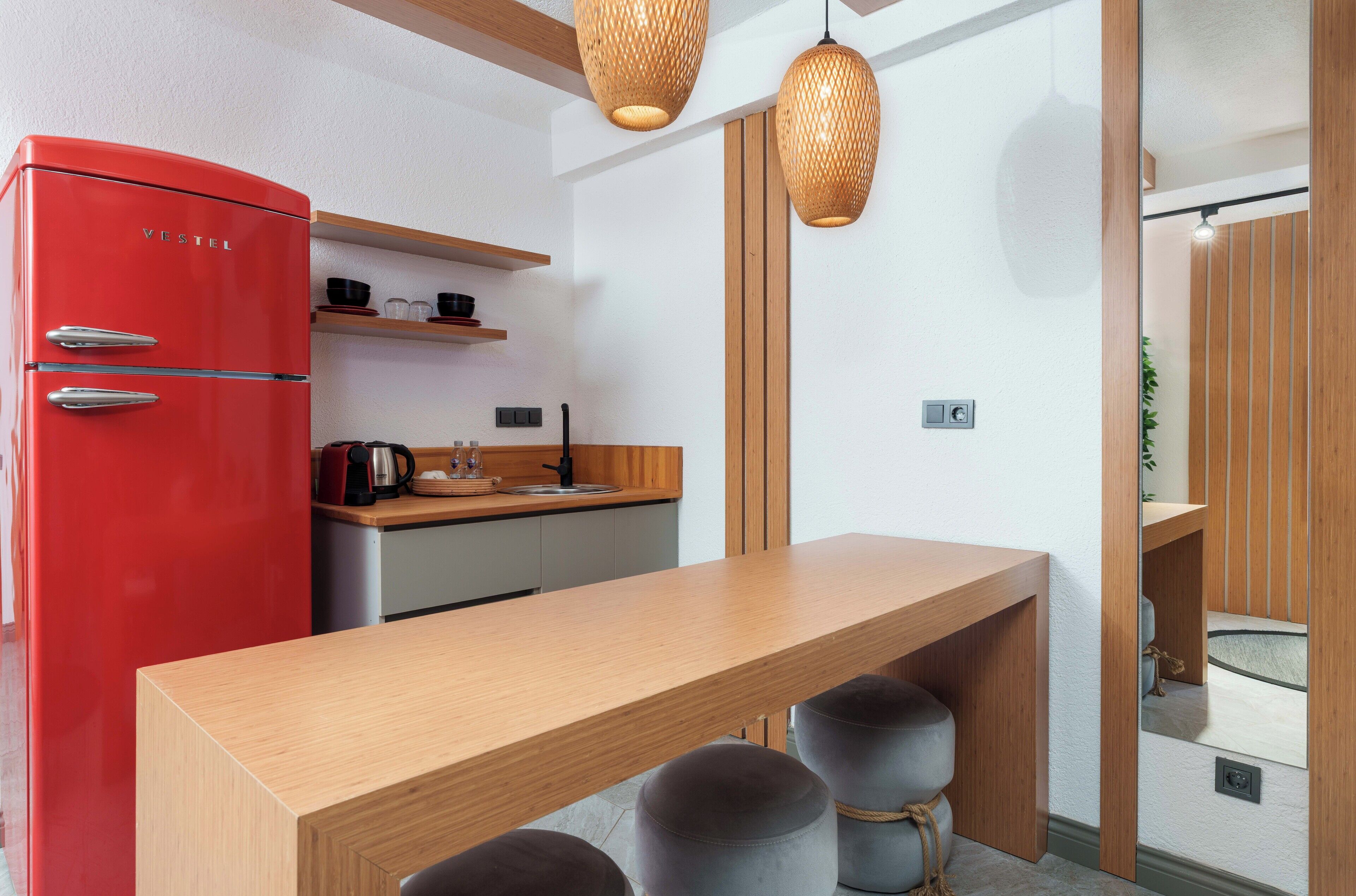 A compact kitchen with a red refrigerator, wooden countertop, and pendant lights.