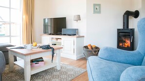 Een gezellige woonkamer met een open haard, een televisie en een comfortabele zithoek.