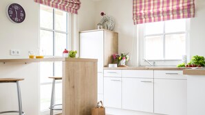 Een moderne keuken met witte kastjes, een houten kookeiland, barstoelen en een raam met uitzicht.