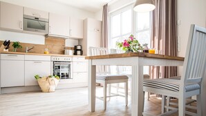 Una cocina moderna con armarios blancos, horno integrado y encimera de madera.