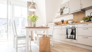 Eine helle Küche mit weißen Schränken, einer Holz Arbeitsplatte und einer hängenden Pendelleuchte.
