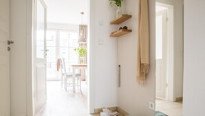 Ein heller Flur mit Holzboden, einem Spiegel und einem kleinen Tisch mit Blumen in einer Vase.