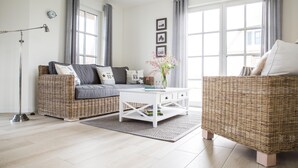 En moderne stue med en grå sofa, et hvidt sofabord og en fletstol.