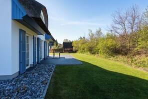 A modern building with a thatched roof, a paved pathway, and a well-maintained lawn. - Ferienhaus Schilfrohrsänger 51 - Der Natur Ganz nah (Fuhlendorf)