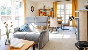 Ein modernes Wohnzimmer mit einem grauen Sofa, einem Holztisch und einem Essbereich mit Tisch und Stühlen.
