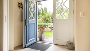 Una puerta con marco azul y paneles de vidrio decorativos, una planta en maceta y un bolso en el suelo.