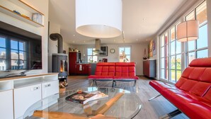A modern living room with a glass coffee table, red leather sofa, and a fireplace.