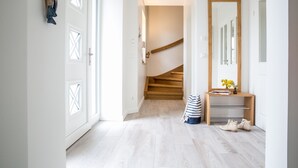 Un corridoio con una scala in legno, uno specchio e una consolle con un vaso e dei libri.