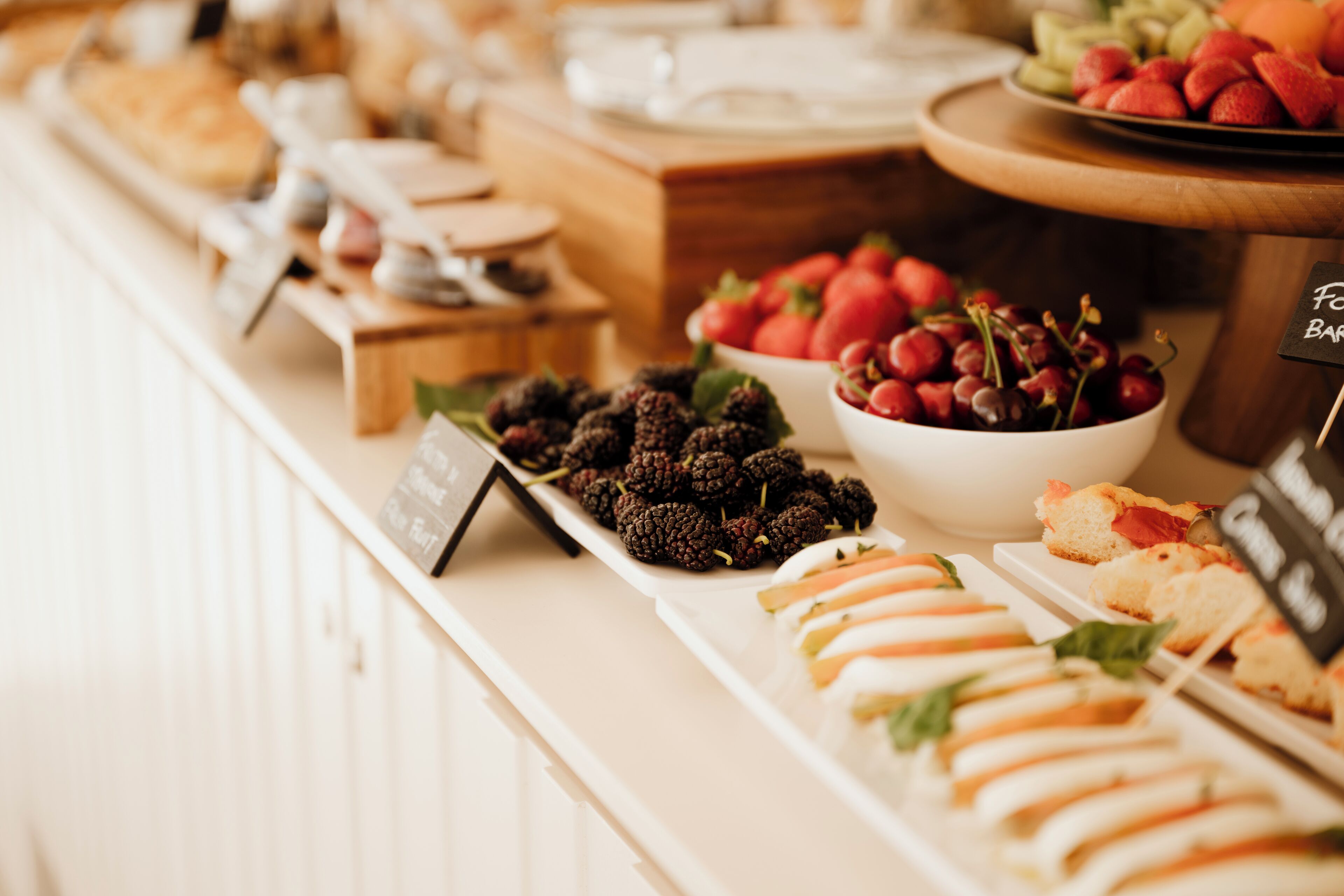 Un bufé con diversas opciones de comida, como frutas, quesos y pastelería.