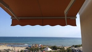 A beach view from a covered balcony with a clear sky. - VIEW OF THE MEDITERRANEAN SEA (La Grande-Motte)
