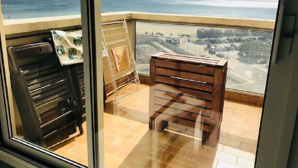 A balcony with a view of the sea, a wooden bench, and a metal rack with towels. - VIEW OF THE MEDITERRANEAN SEA (La Grande-Motte)